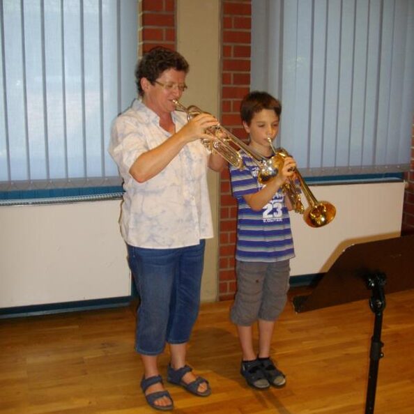 Musiklehrerin und Schüler spielen Trompete